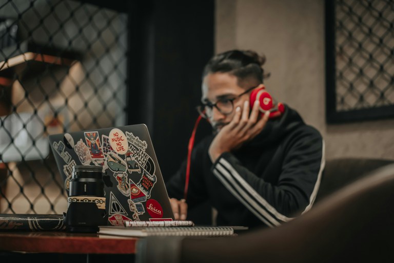 A freelancer is working at his computer, with his hand on his chin and a thoughtful expression on his face.